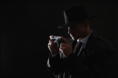 Old fashioned detective with camera on dark background. Space for text