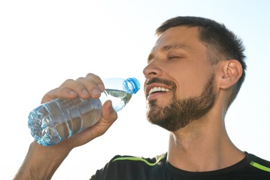 Photo of Happy man drinking water on hot summer day. Refreshing drink