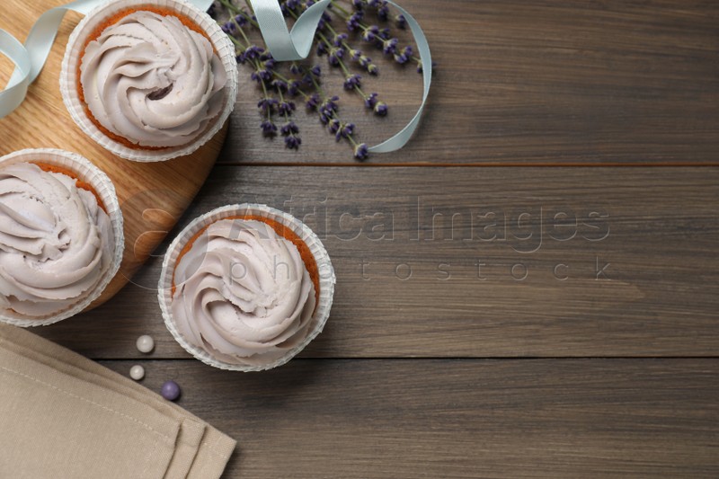 Photo of Tasty cupcakes on wooden table, flat lay. Space for text