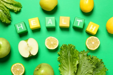 Photo of Word Health made with cubes and different fresh products on green background, flat lay