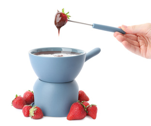 Woman dipping strawberry into fondue pot with chocolate on white background, closeup