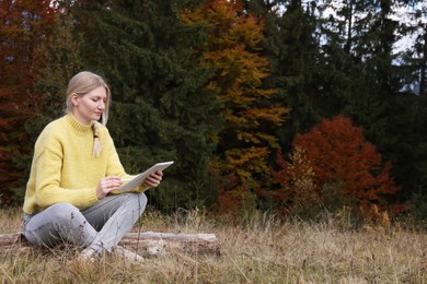 Photo of Young woman drawing with graphic tablet near forest in autumn