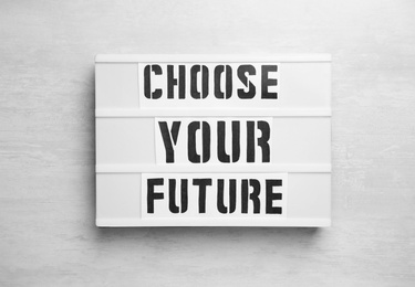 Board with words CHOOSE YOUR FUTURE on white wooden background, top view. Career concept