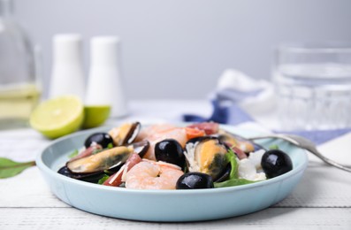 Photo of Plate of delicious salad with seafood on white wooden table