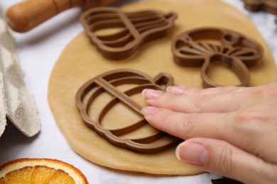 Woman making biscuits with cookie cutters on white table, closeup