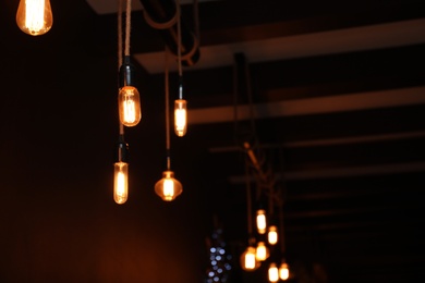 Glowing lamp bulbs in dark room. Space for text