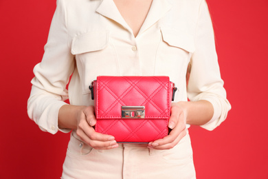 Young woman in casual outfit with stylish bag on red background, closeup