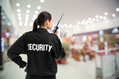 Image of Security guard using portable radio transmitter in shopping mall, space for text