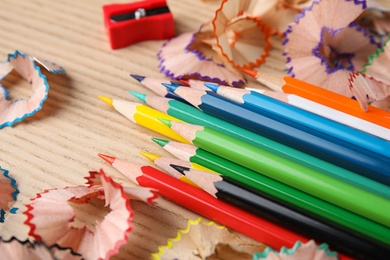 Color pencils, sharpener and shavings on wooden table, closeup