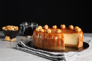 Photo of Sliced delicious cheesecake with caramel and popcorn on light grey table, space for text