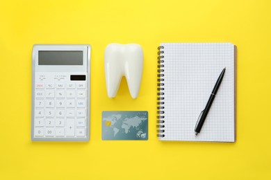 Flat lay composition with ceramic model of tooth and credit card on yellow background. Expensive treatment