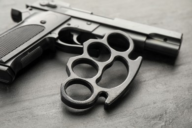 Brass knuckles and gun on black background, closeup