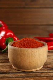 Bowl of paprika with peppers on wooden table, closeup