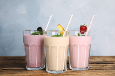 Different tasty milk shakes on wooden table