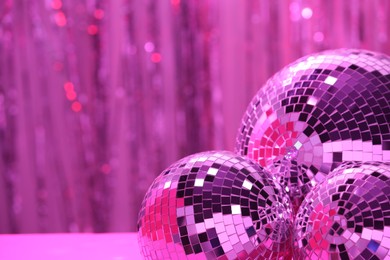 Photo of Shiny disco balls on blurred background, toned in pink. Space for text