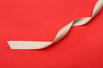 Beautiful ribbon on red background, top view