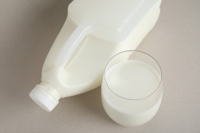 Gallon bottle and glass of milk on beige background