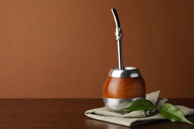 Calabash with mate tea and bombilla on wooden table. Space for text