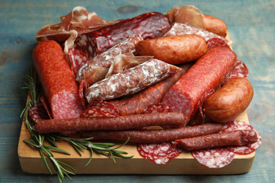 Different types of sausages served on light blue wooden table, closeup