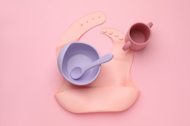 Baby feeding accessories and bib on pink background, flat lay