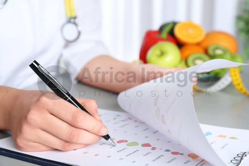 Female nutritionist with list of products at table, closeup
