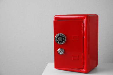 Red steel safe on table against light wall. Space for text
