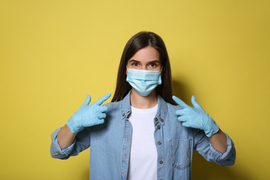 Female volunteer in mask and gloves on yellow background. Protective measures during coronavirus quarantine