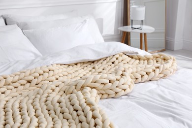 Soft chunky knit blanket on bed indoors