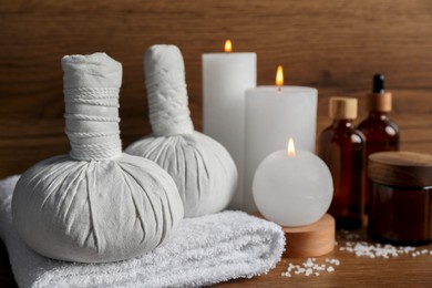 Photo of Beautiful spa composition with different care products and burning candles on wooden table, closeup. Space for text