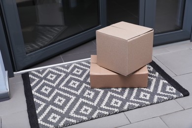 Cardboard boxes on stylish door mat near entrance