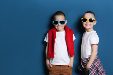 Portrait of cute twin brothers with sunglasses on color background. Space for text