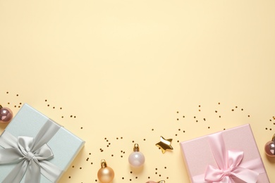 Beautiful gift boxes, Christmas balls and golden confetti on beige background, flat lay. Space for text
