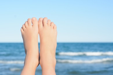 Child resting near sea, closeup of feet. Space for text