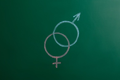 Gender symbols drawn on green chalkboard. Sex education