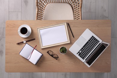 Photo of Chair near wooden table with laptop, cup of coffee and stationery indoors, top view
