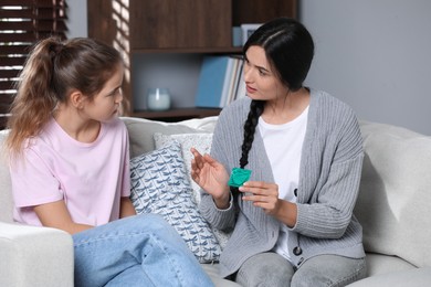 Mother talking with her teenage daughter about contraception at home. Sex education concept