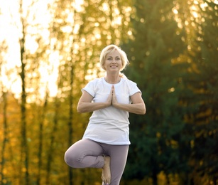 Happy mature woman practicing yoga in park. Active lifestyle