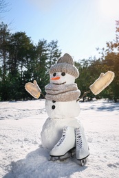 Funny snowman with hat, mittens and scarf in winter forest on sunny day
