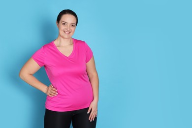 Photo of Happy overweight woman on light blue background, space for text