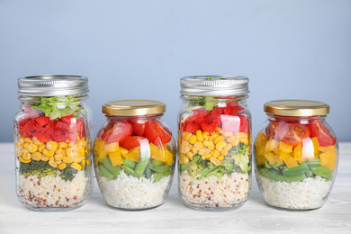Glass jars with healthy meal on white wooden table