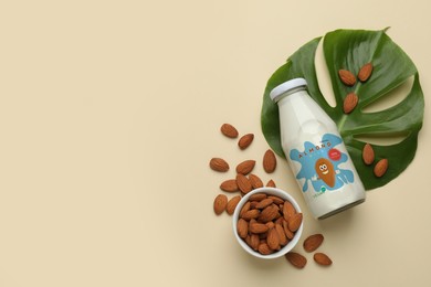 Bottle of almond milk and nuts on beige background, flat lay with space for text. Vegan product