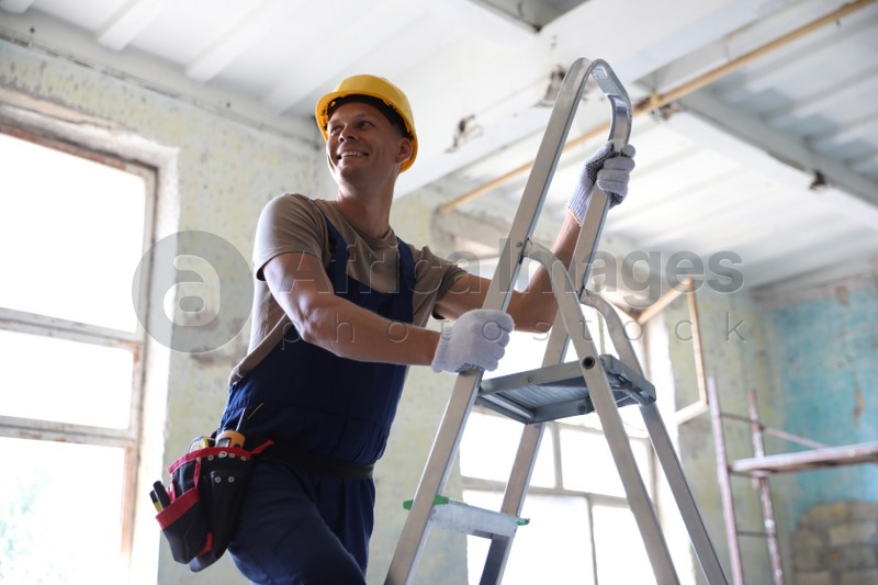 Photo of Professional constructor on ladder in old building