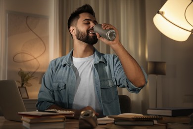 Young man with energy drink studying at home