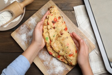 Woman making Stollen with candied fruits and raisins on wooden board at table, top view