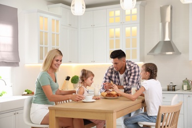 Happy family eating together at table in modern kitchen