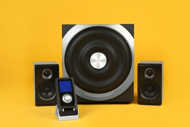 Modern powerful audio speaker system with remote on yellow background