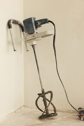 Photo of Power mixer on floor near wall indoors. Tiles installation process