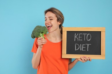 Woman holding blackboard with phrase Keto Diet and broccoli on light blue background