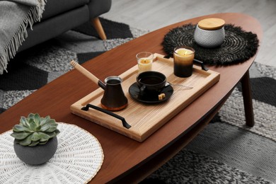 Tray with freshly made coffee and decorative elements on wooden table in room
