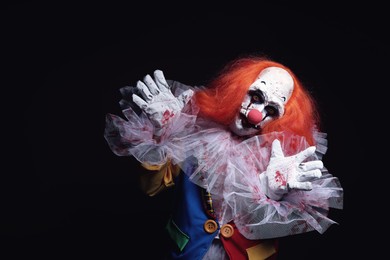Photo of Terrifying clown on black background, space for text. Halloween party costume